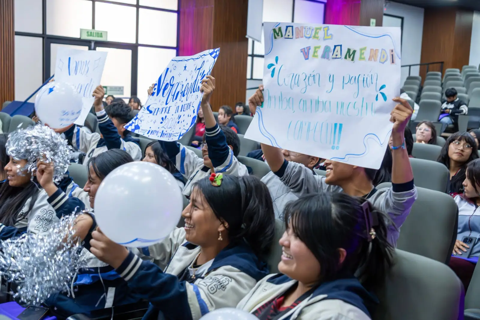 Estudiantes alentando con carteles y globos