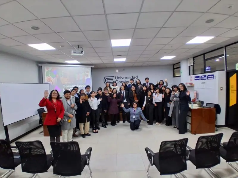 Equipo interdisciplinario de estudiantes trabajando con notas adhesivas sobre un muro de vidrio